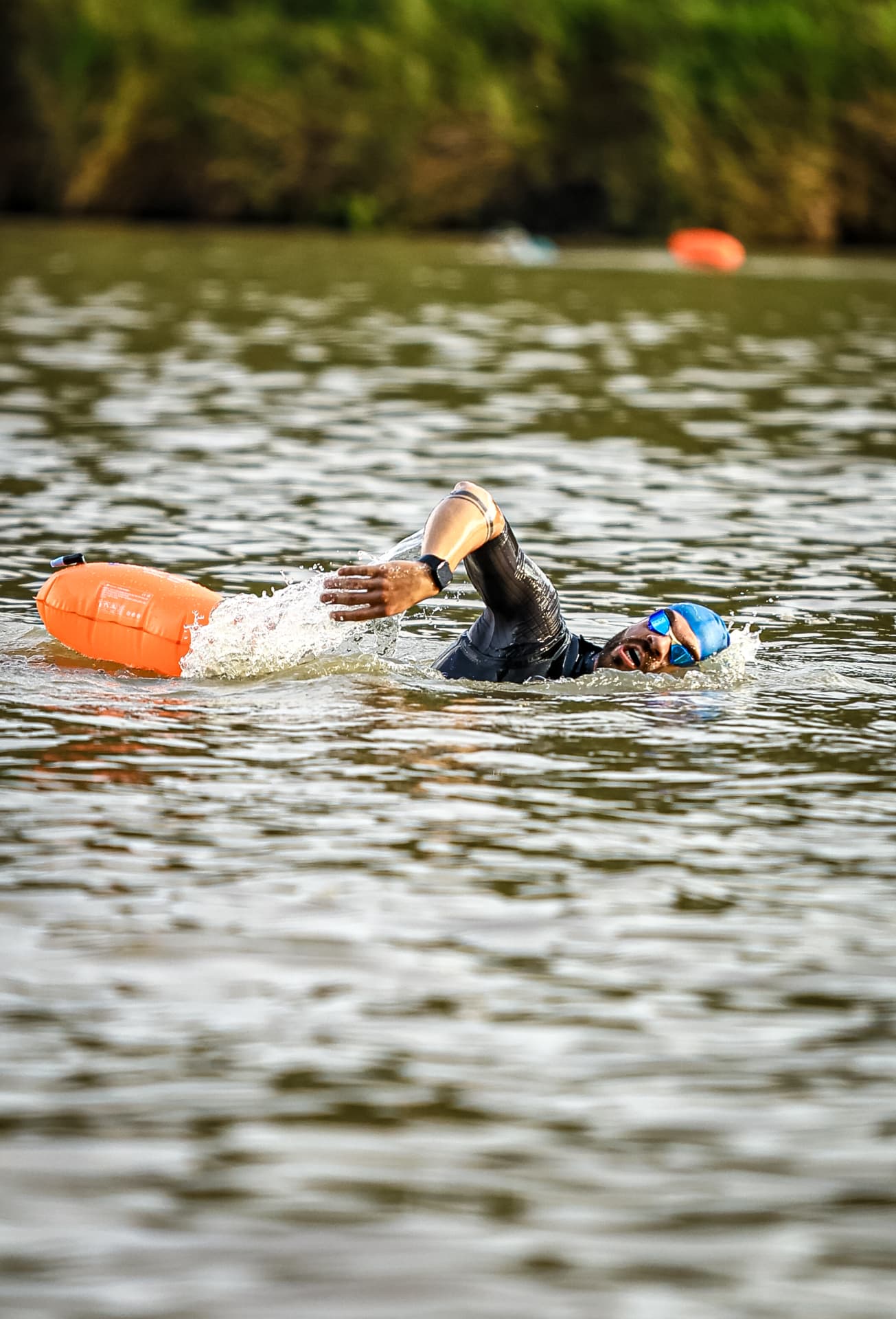 Triatleta nadando com boia de segurança laranja