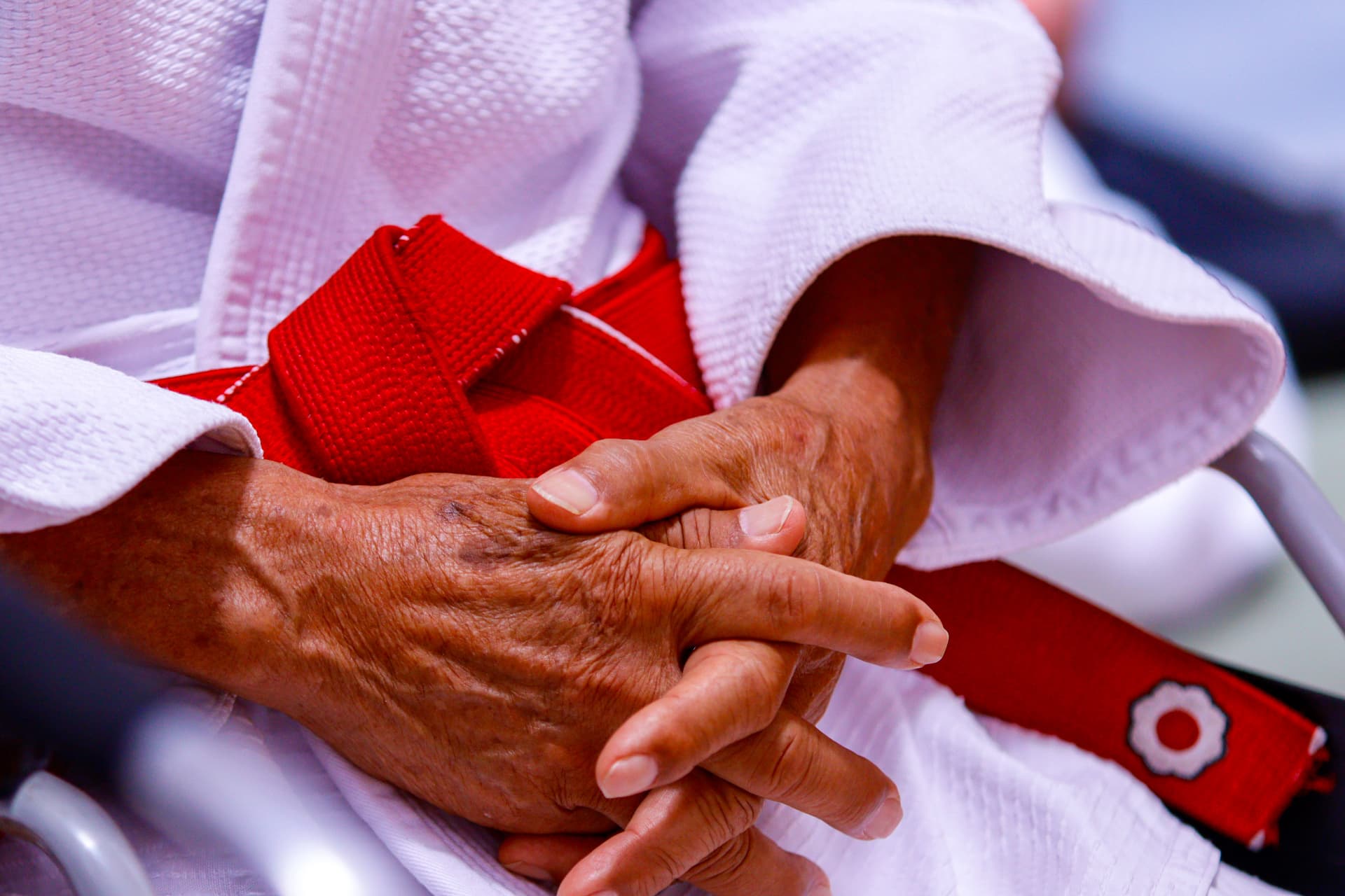 Detalhe das mãos com a faixa vermelha do judô