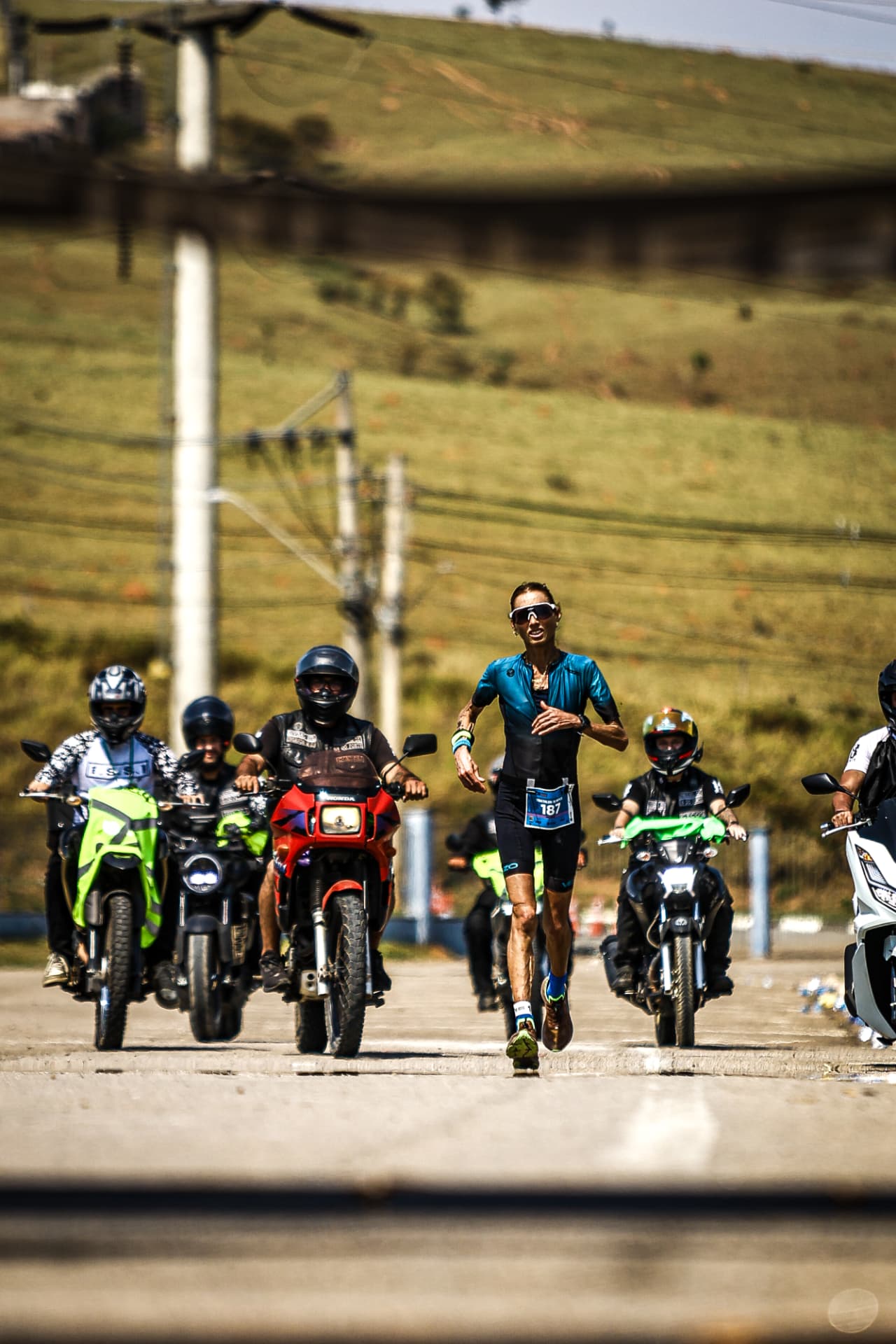 Corredor em prova cercado por motociclistas